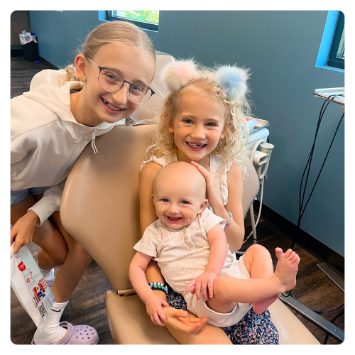 Three happy siblings smiling in the dental chair