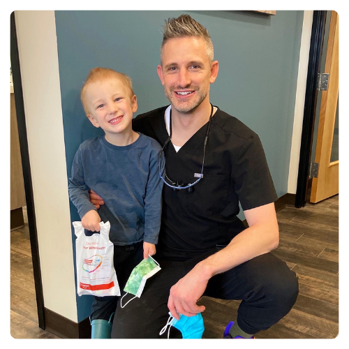 Dr. Davis with a smiling young patient holding a goodie bag