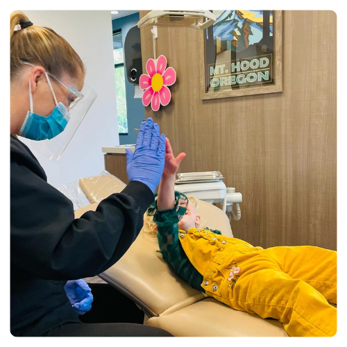 A team member high-fives a happy young patient at Sunnyside Dentistry for Children
